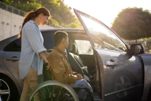 Individual with disabilities helped with a woman into car from wheelchair